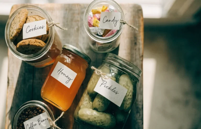 Collection of mason jars with funny pun labels sealed with colorful lids on a rustic wooden table